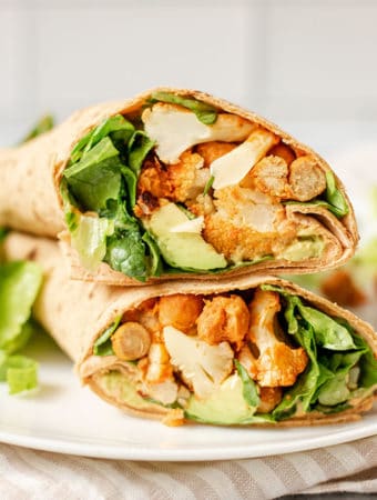 Chickpea cauliflower wraps sitting on top of each other on a plate, filling facing towards you.