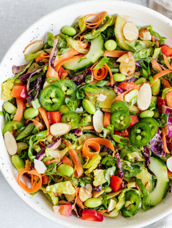 Giant bowl of edamame crunch salad plated with extra jalapeno slices.