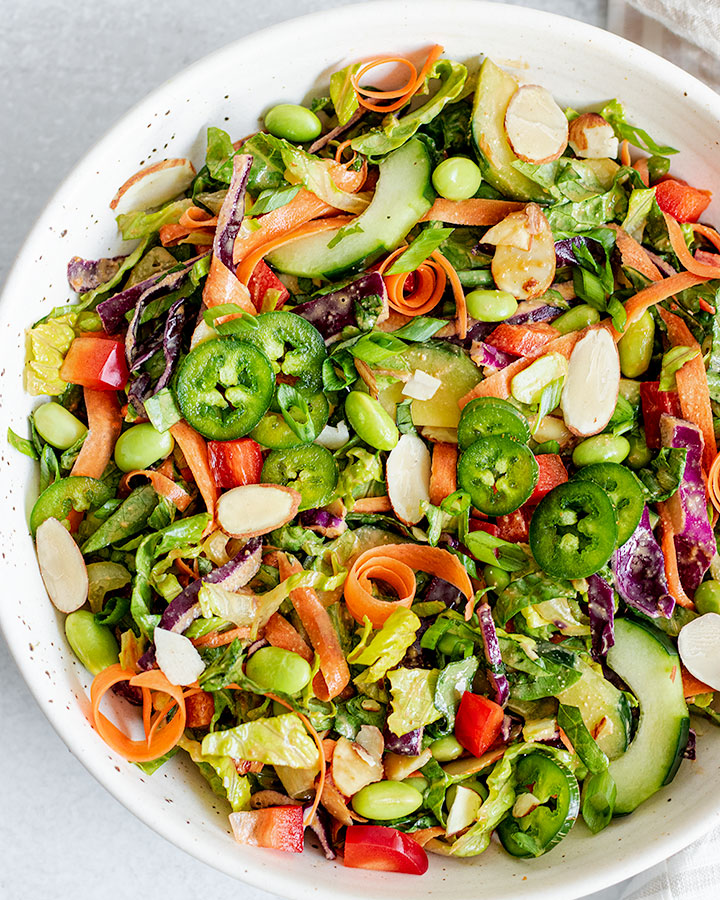 Giant bowl of edamame crunch salad plated with extra jalapeno slices.