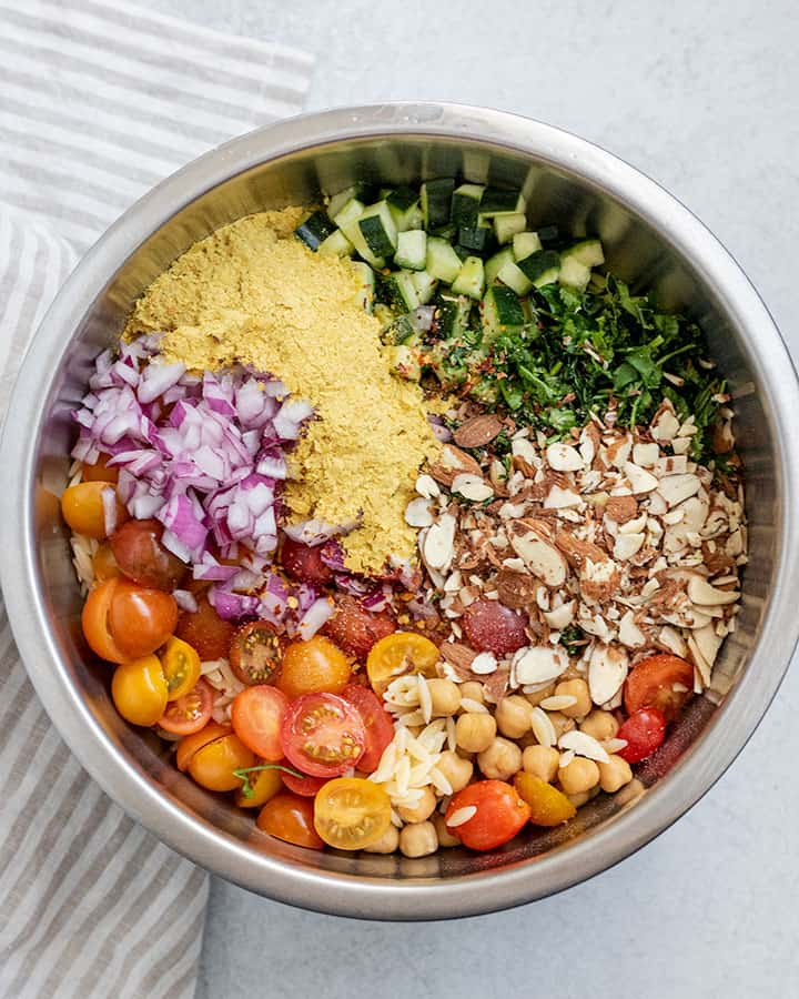 All salad ingredients piled into a bowl in separate categories before mixing.