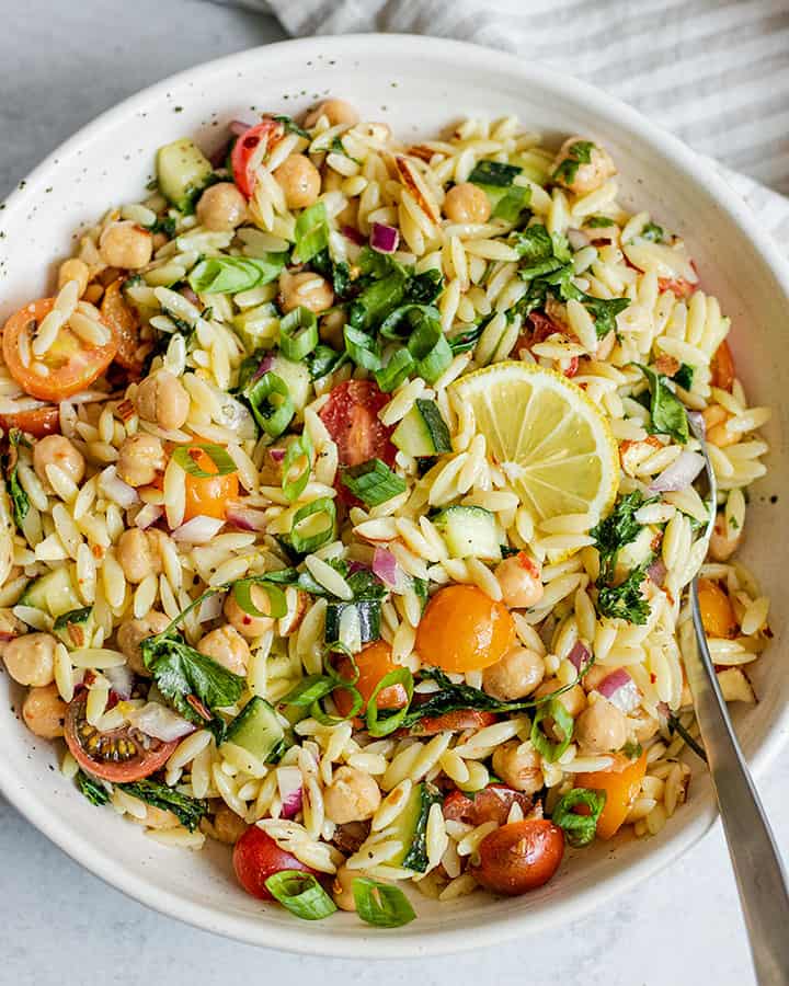 Orzo pasta salad mixed and served in a white bowl.