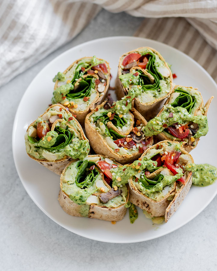 Plate of pesto pinwheels next to a stripped napkin.