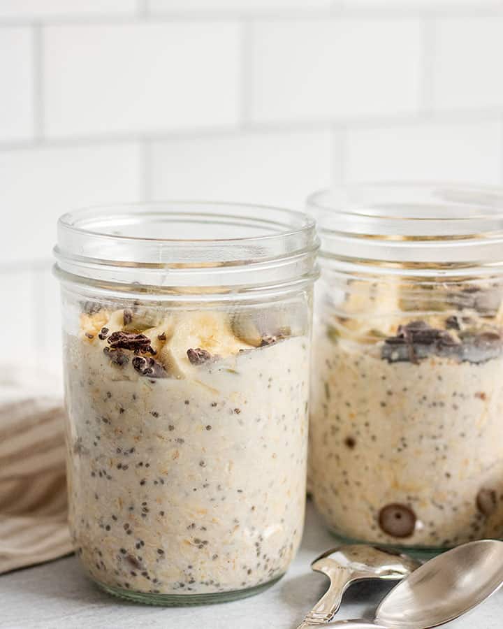 Two decorated oatmeal jars sitting on a stripped napkin.