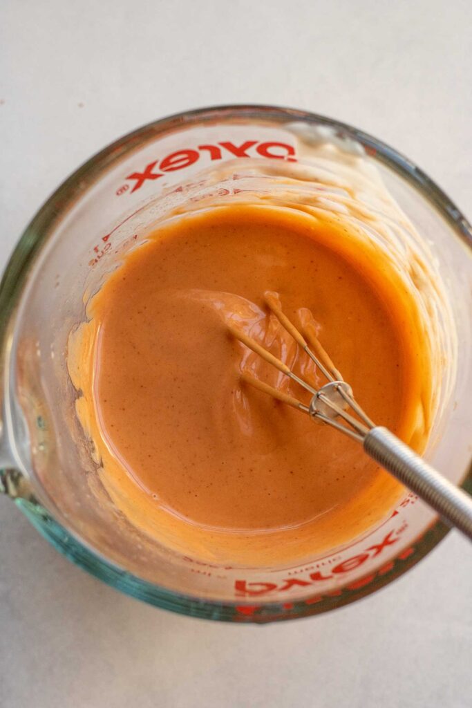 Mixing the creamy buffalo sauce together in a large measuring cup with a small whisk.