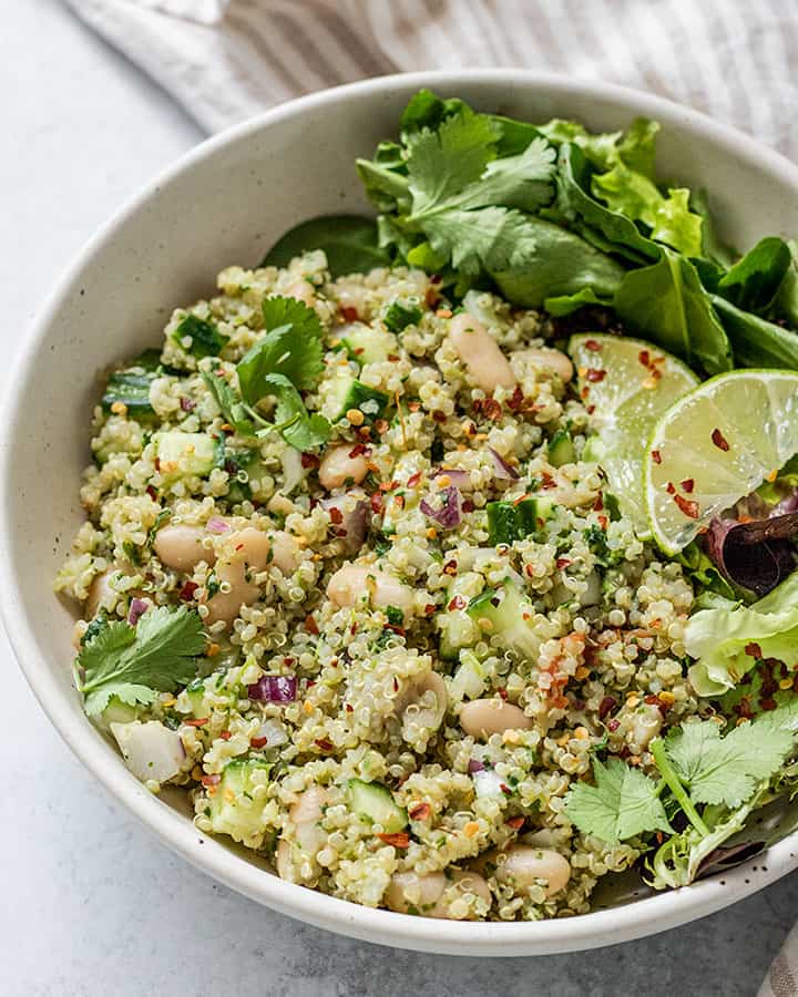 Side angle view of quinoa salad paired with lime wedges.