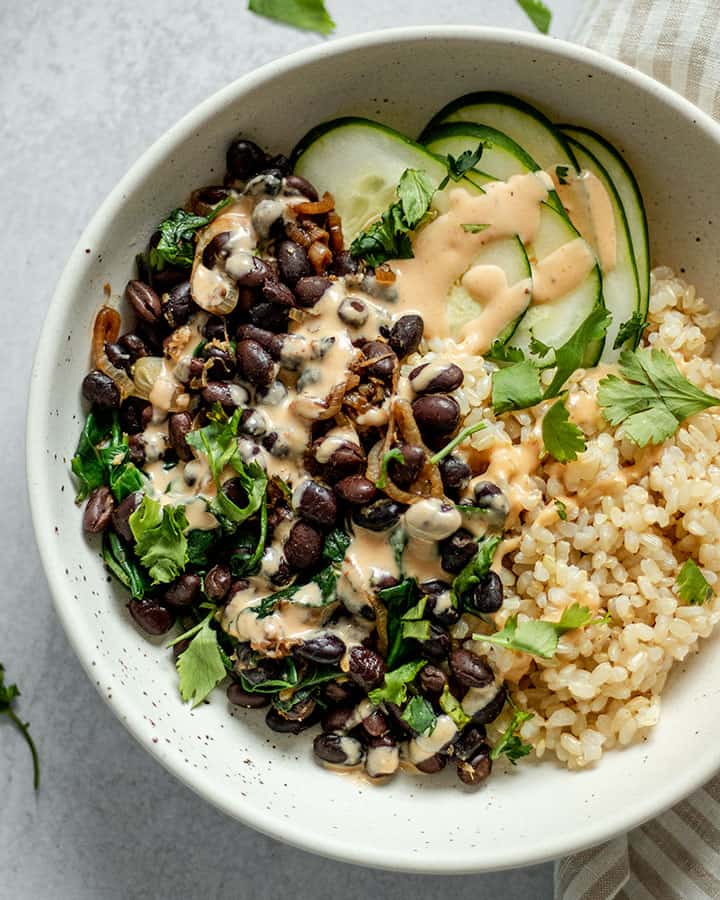 Black beans with rice vegetables and sauce topped over it.