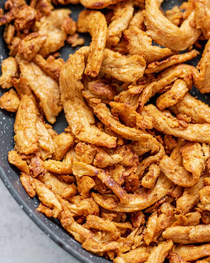 Close up of cooked soy curls in a black pan.