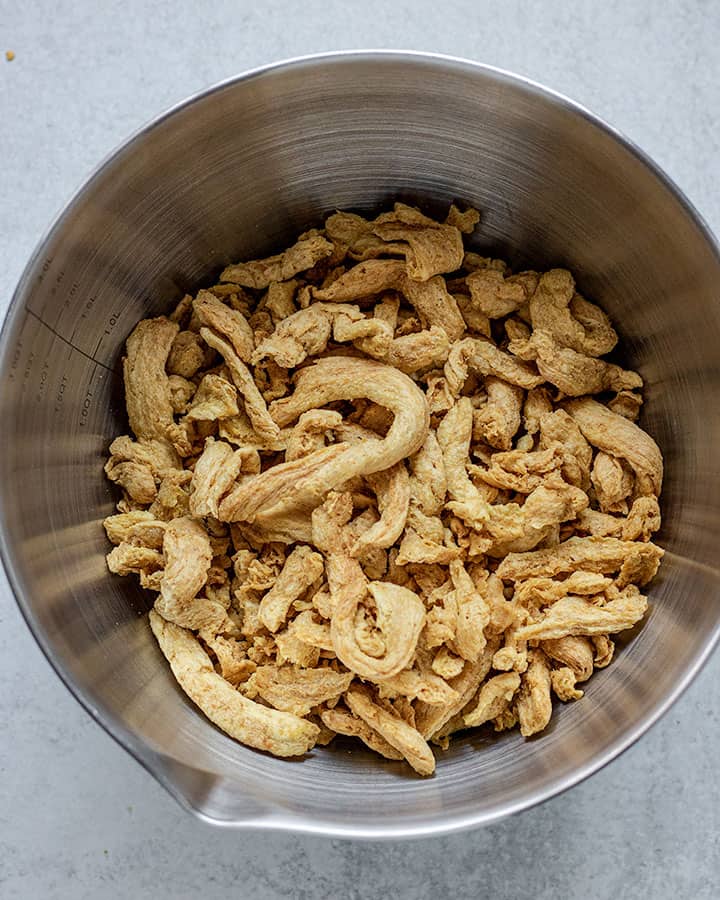 Dry soy curls sitting in a large metal bowl.