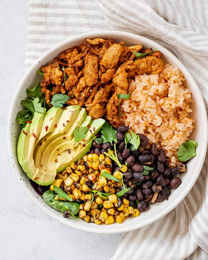 Fully assembled nourish bowl with Mexican rice, soy curls, black beans, fire roasted corn and avocado.