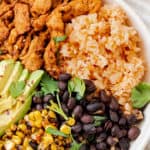 Plate of Mexican rice paired with soy curls, black beans, corn and avocado.