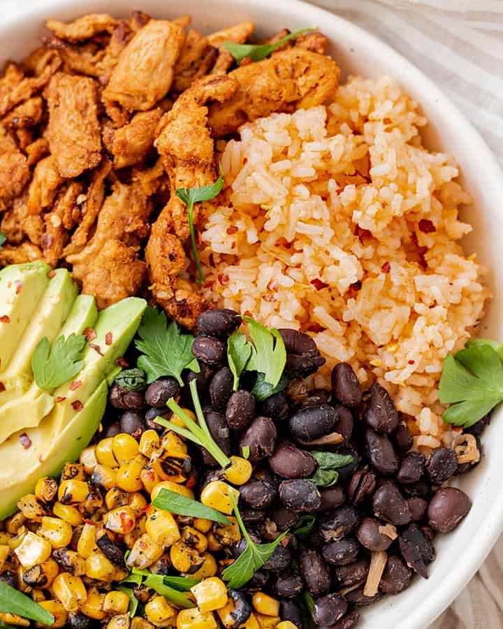 Plate of Mexican rice paired with soy curls, black beans, corn and avocado.