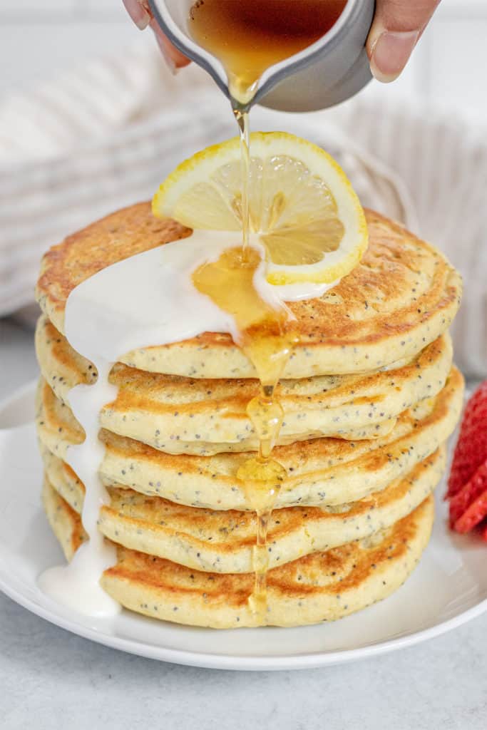 Stack of pancakes being served with maple syrup.