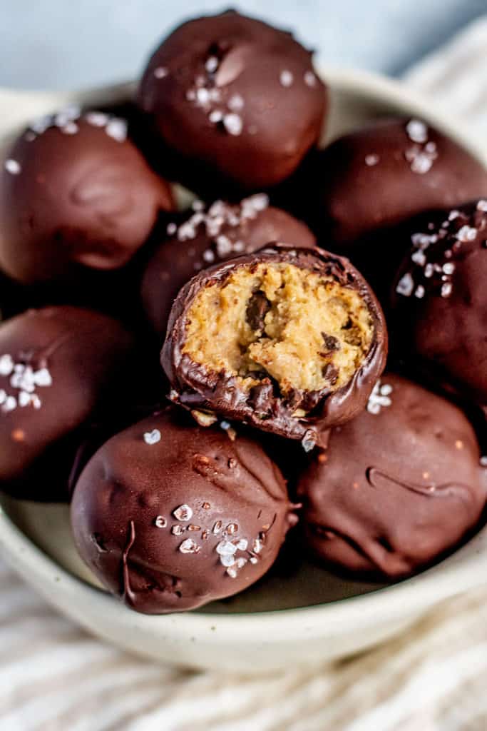 Chocolate coated chickpea bite with a bite out of it sitting on top of other bites.