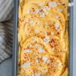 Mango sorbet swirled into a metal pan and topped with spices and coconut.