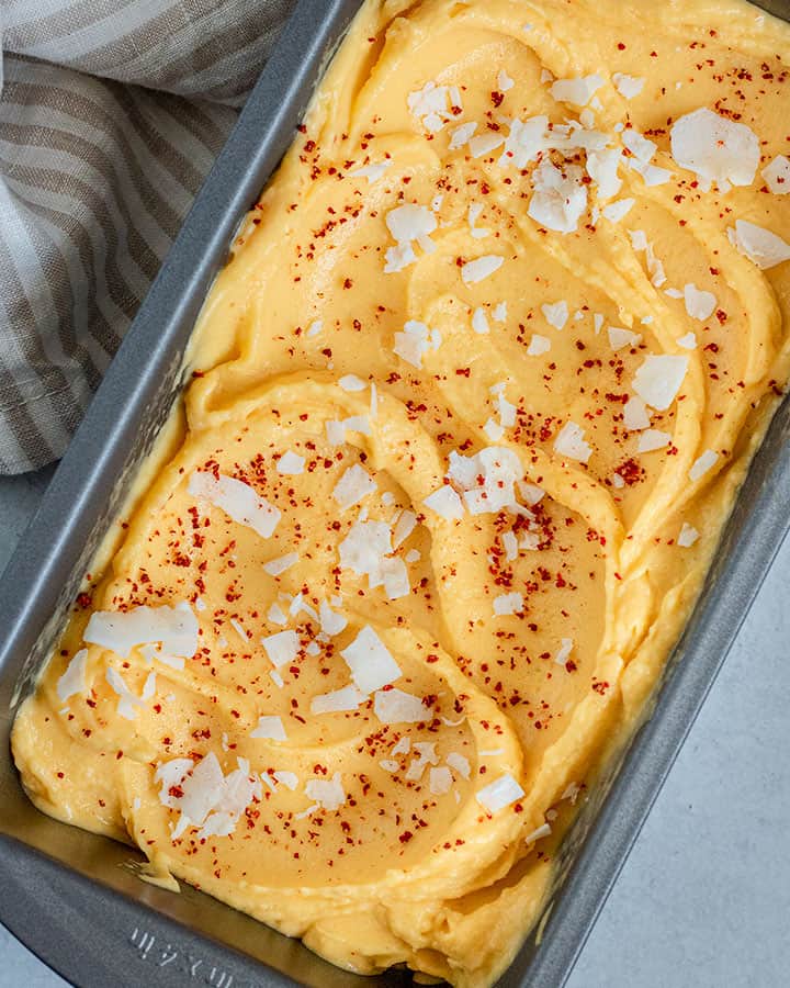 Side view of the mango sorbet swirled into a metal dish.