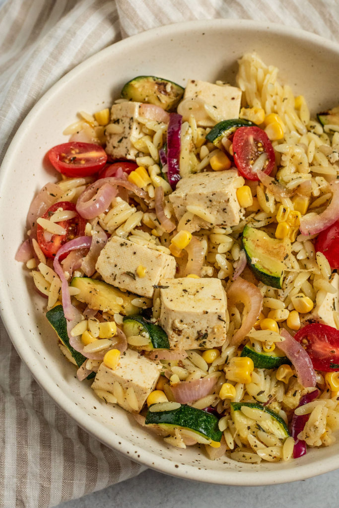 Close up of marinated tofu combined with grilled vegetables and orzo.