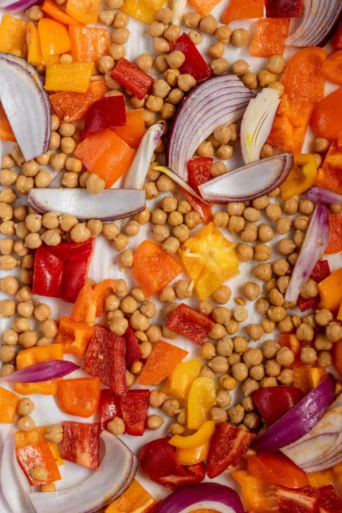Sheet pan with oiled and spiced chickpeas, onions and peppers.