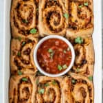 Pinwheels served in a baking tray with salsa.