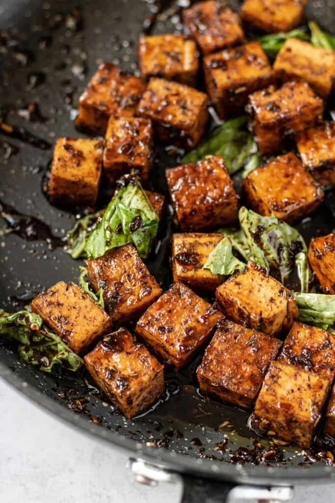 Pan of freshly cooked tofu in a balsamic reduction and fresh basil.