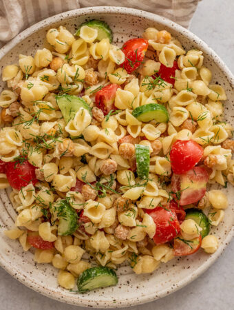 A plate of chickpea pasta salad tossed with fresh chopped veggies and dressing.