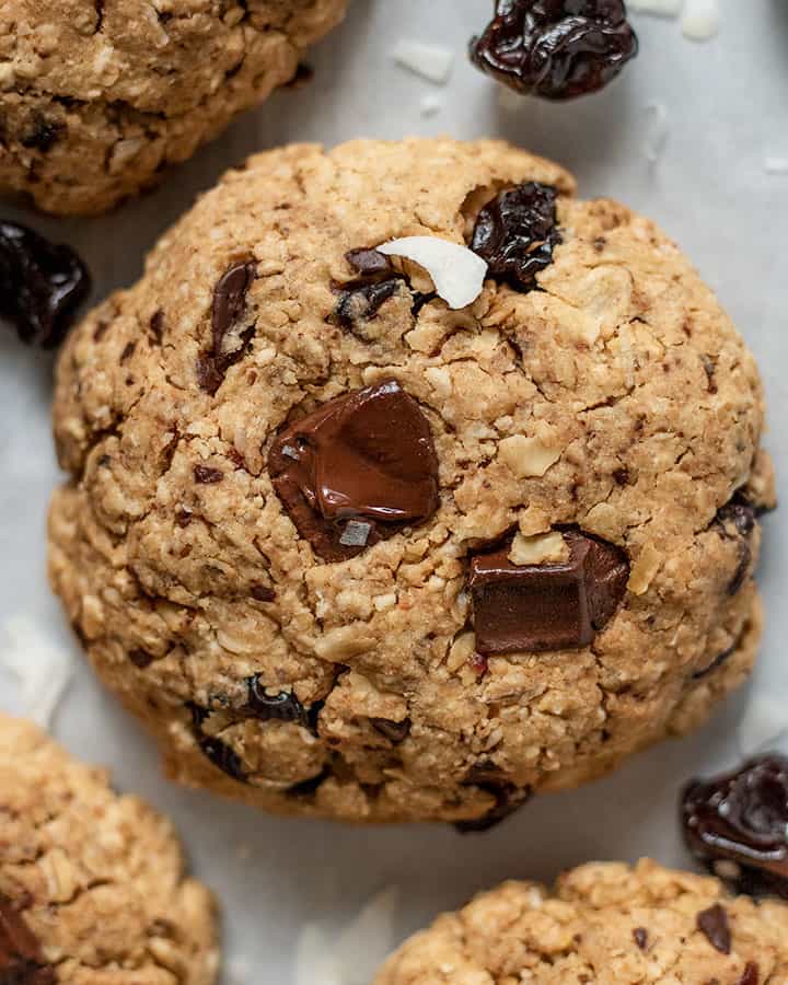 Close up of one breakfast cookie with dried cherries and coconut flakes shattered around it.