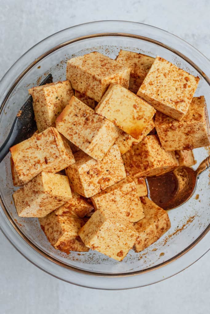 Tossing the cubed tofu into the marinade.