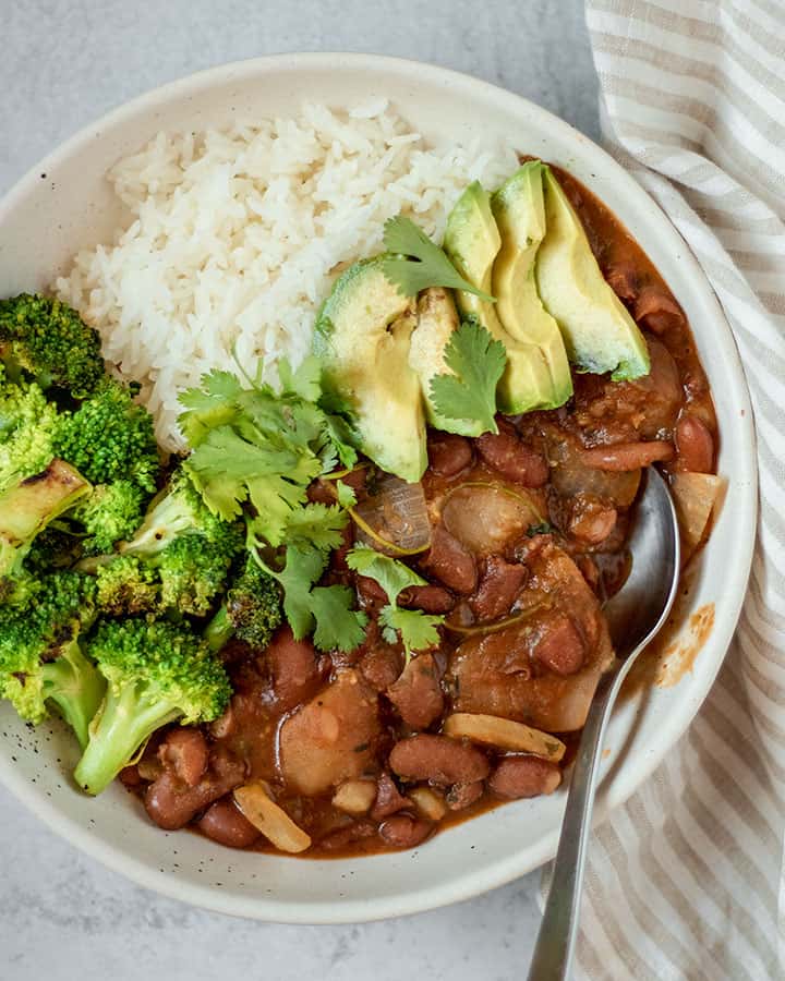 Close up of stewed beans paired with broccoli, avocado and cilantro.
