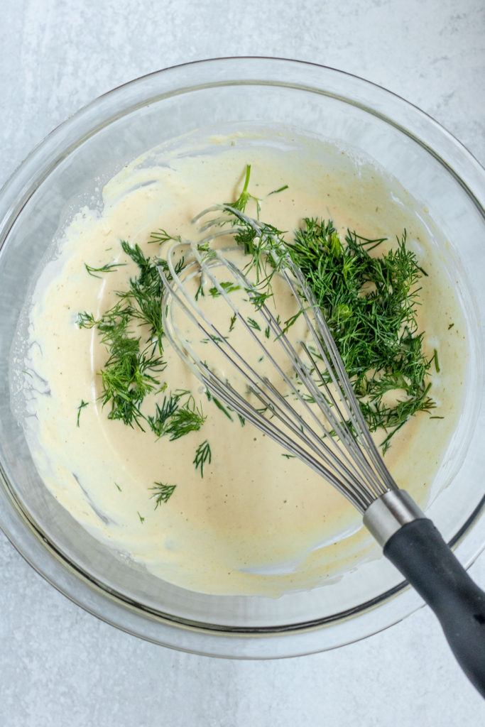 Creamy tahini dressing with dill folded into the bowl.