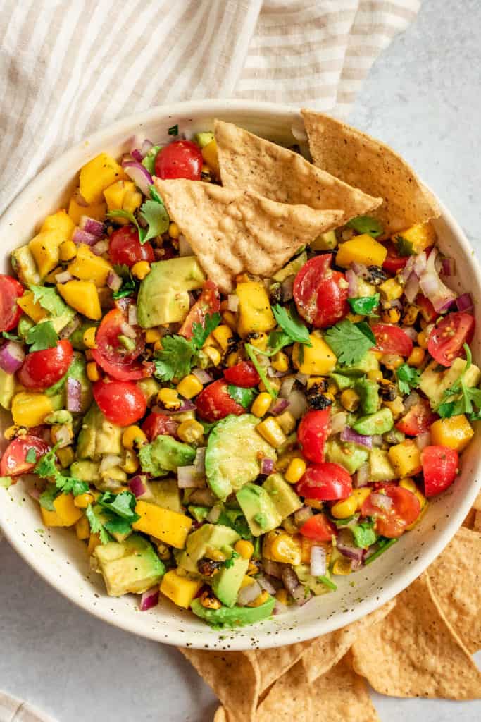 Bowl of mango avocado salsa with chips tucked in on the side.