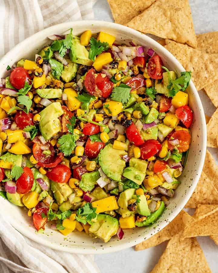 Bowl of avocado mango salsa served with chips on the side.