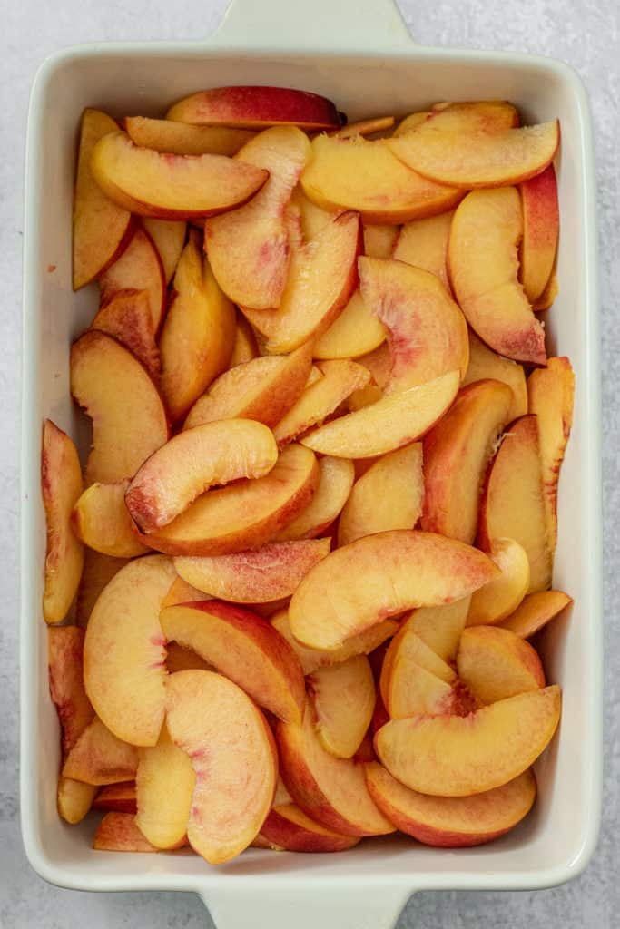 Baking dish filled with freshly sliced ripe peaches.