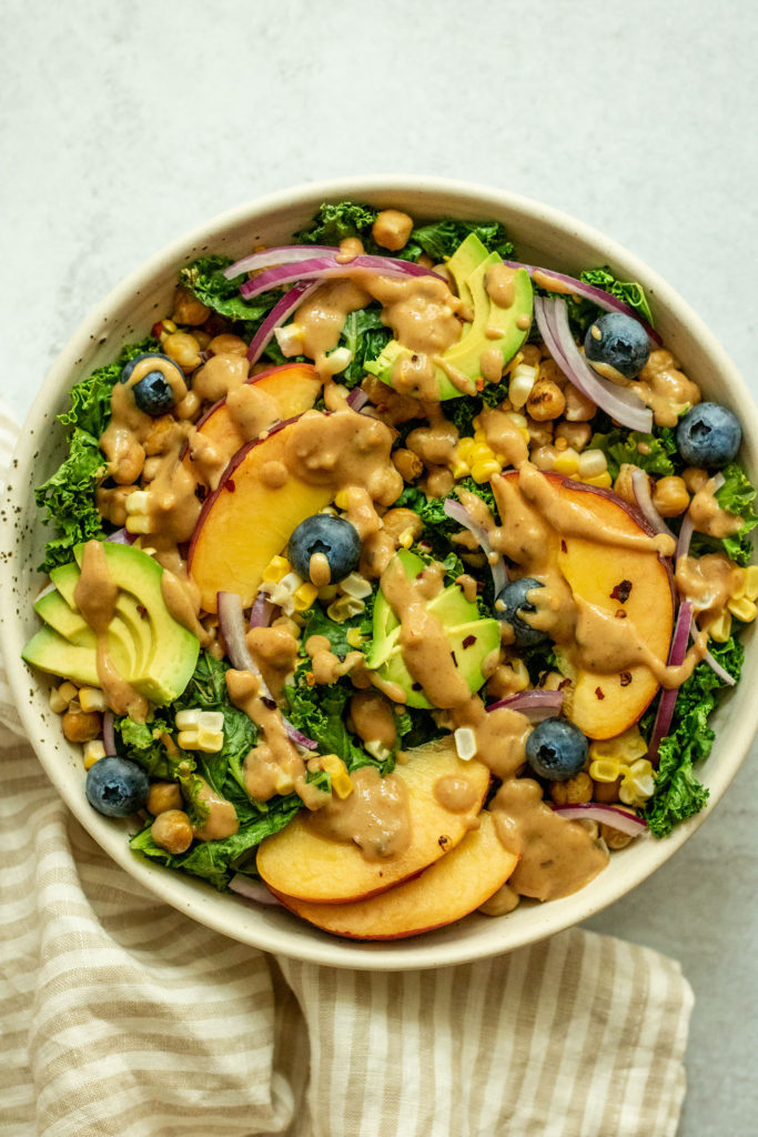 Close up of peach avocado salad topped with a drizzle of sweet cashew mustard sauce.