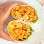 Loaded chickpea curry wrap cut and held together to view the inside.