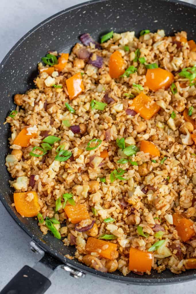 Side view of stir fried cauliflower rice in a large pan.