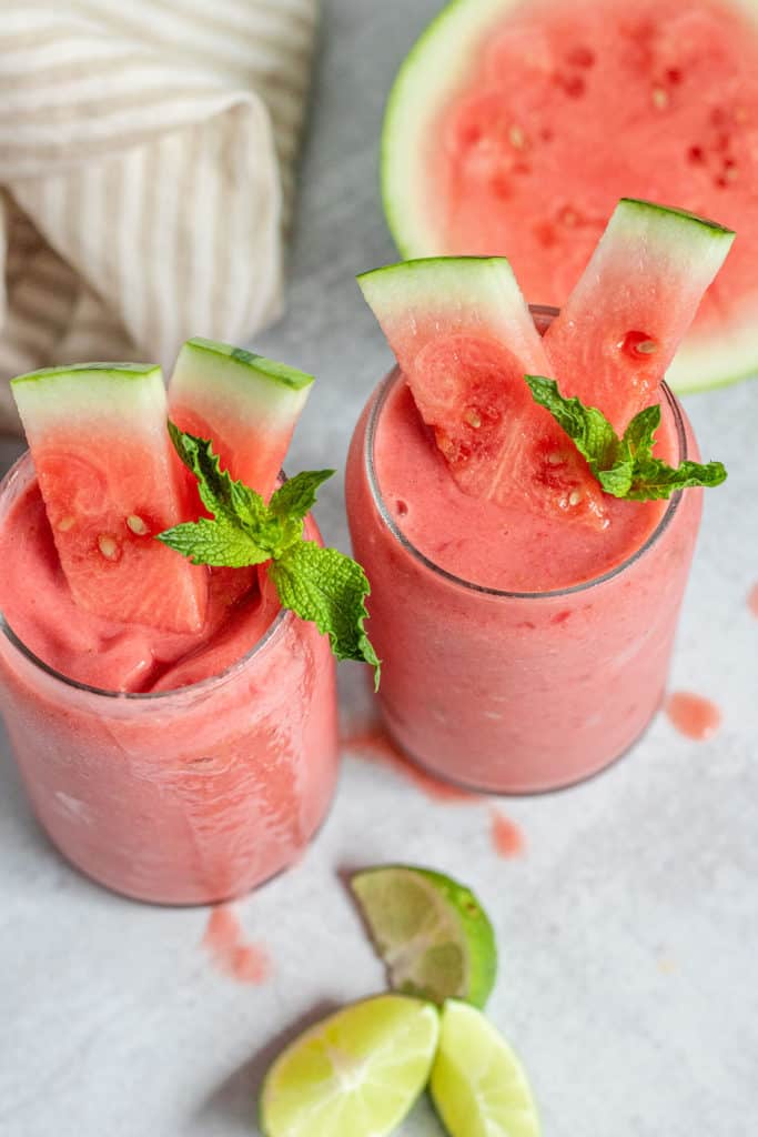 Glasses of watermelon smoothie topped with watermelon cubes and mint.
