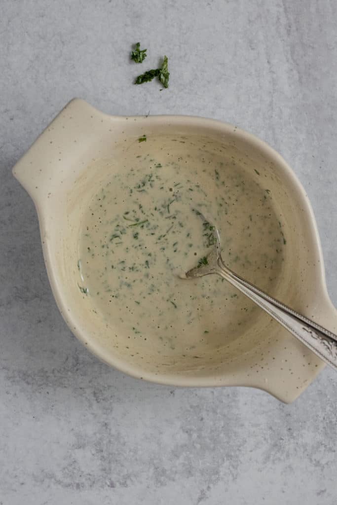 Creamy tahini herb dressing mixed together in a bowl.