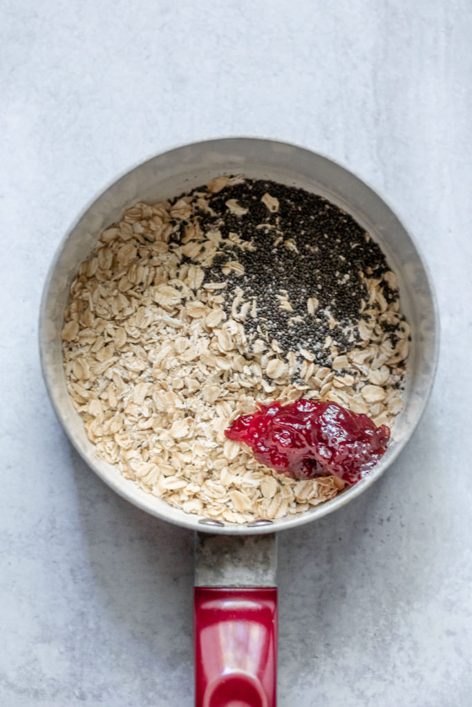 Sauce pan with oats, chia seeds and strawberries preserve.