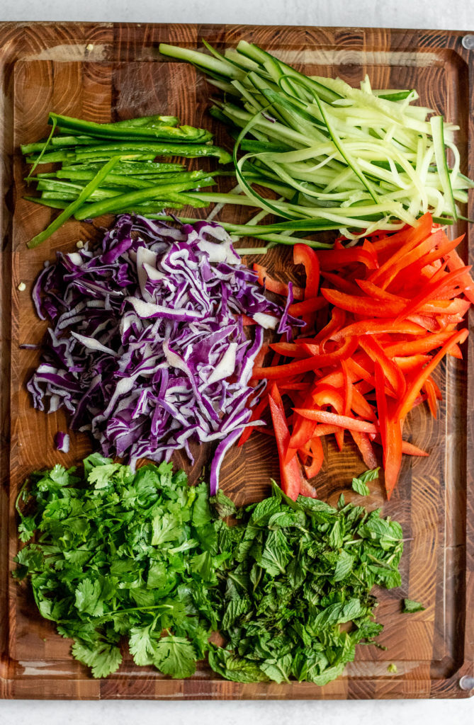 Chopping extra vegetables on a large wooden cutting board.