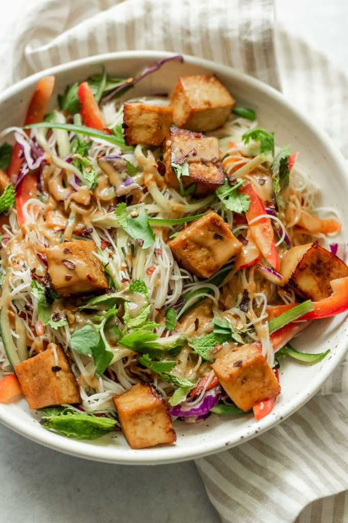 Side view of noodles with tofu, and peanut sauce.