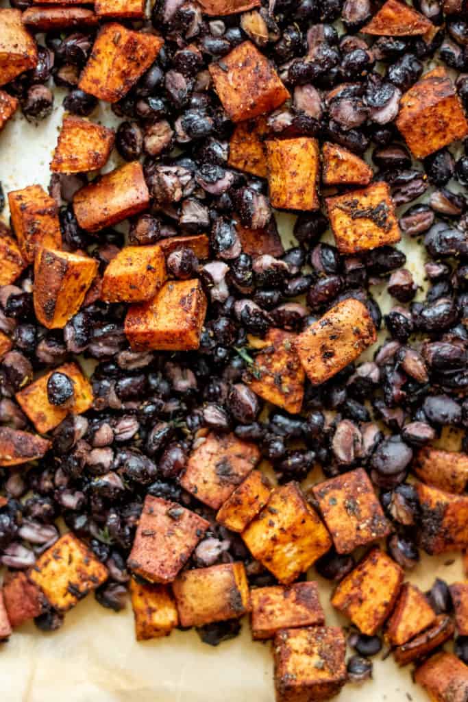 Roasted potatoes and black beans mixed together on a sheet pan.