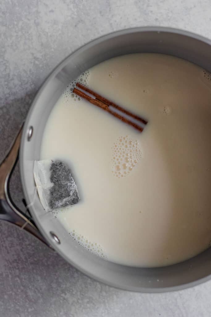 Sauce pan with milk, cinnamon stick and a secured tea bag steeping.