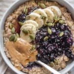 Big bowl of earl grey infused oatmeal topped with banana, stewed berries and nut butter.