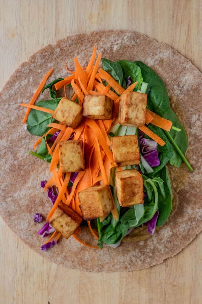 Wrap topped with sriracha mayo, spinach, cabbage, shredded carrots, cucumbers and tofu.
