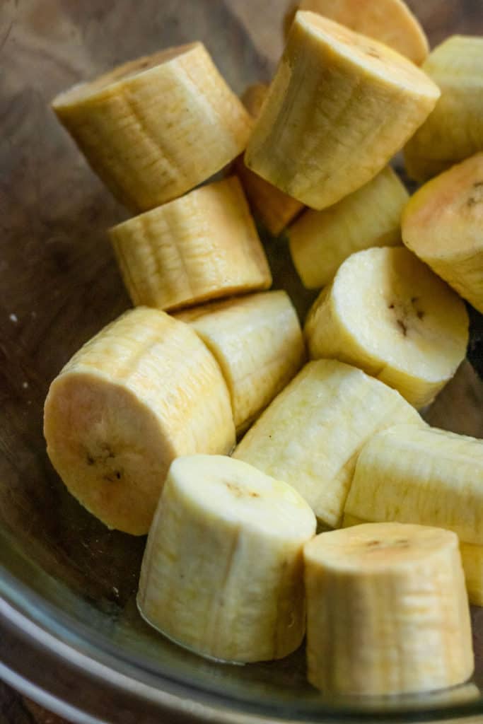 Coating some sliced plantains with some oil.