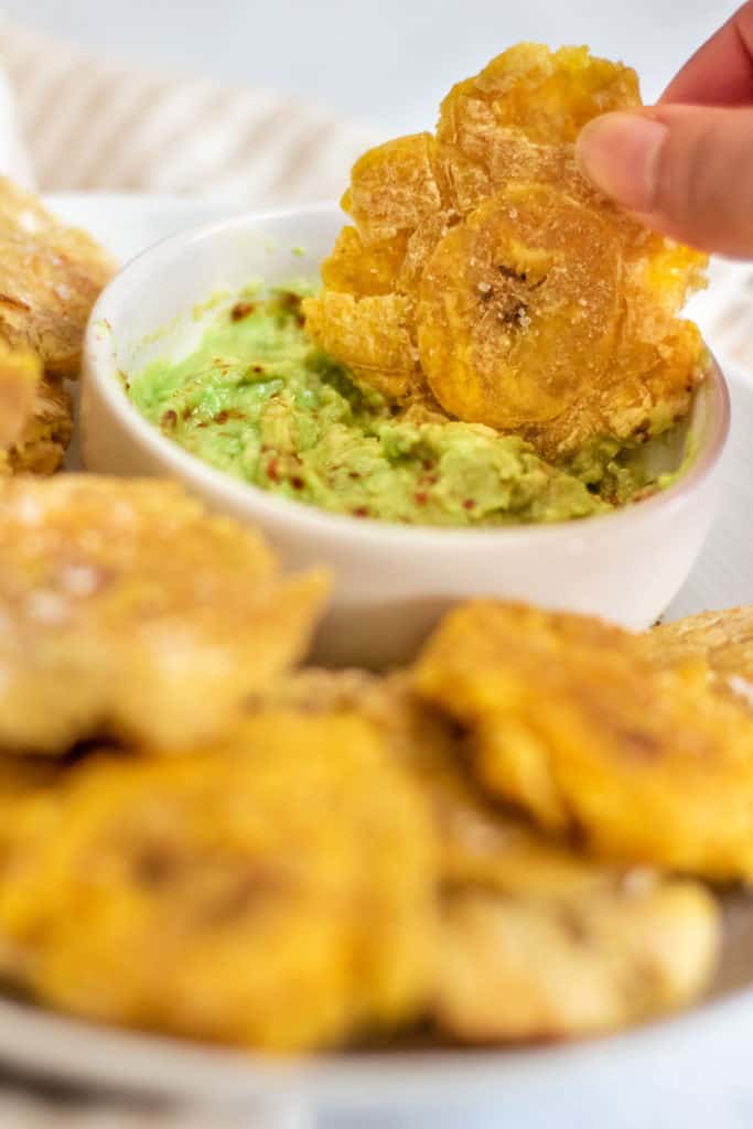 Dunking a twice air fried plantain into some mashed avocado.