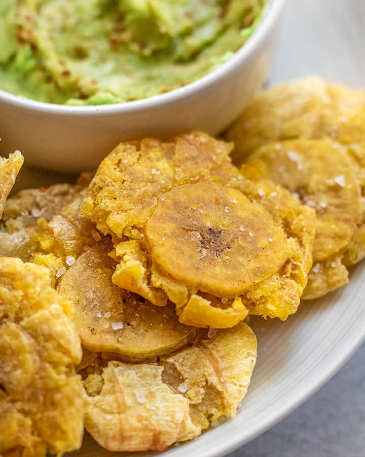 Close up of some fried plantains that were cooked in an air fryer sitting on a white plate.