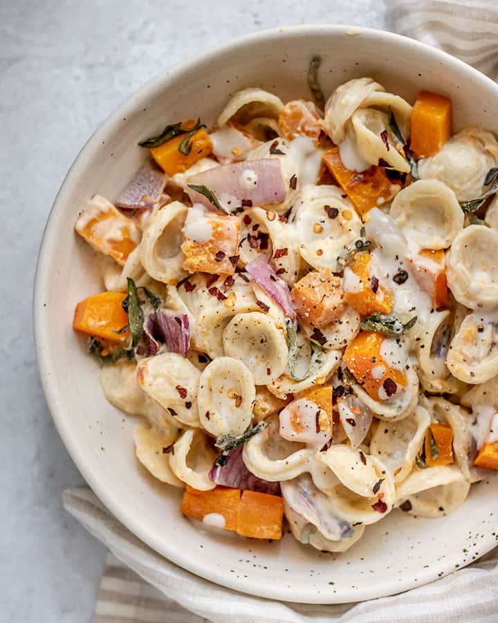 Close up of roasted butternut squash, onions, sage and pasta mixed all together in a bowl.