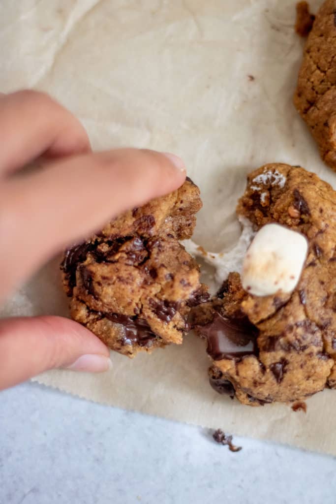 Pulling apart a warm cookie filled with marshmallows and chocolate chips.