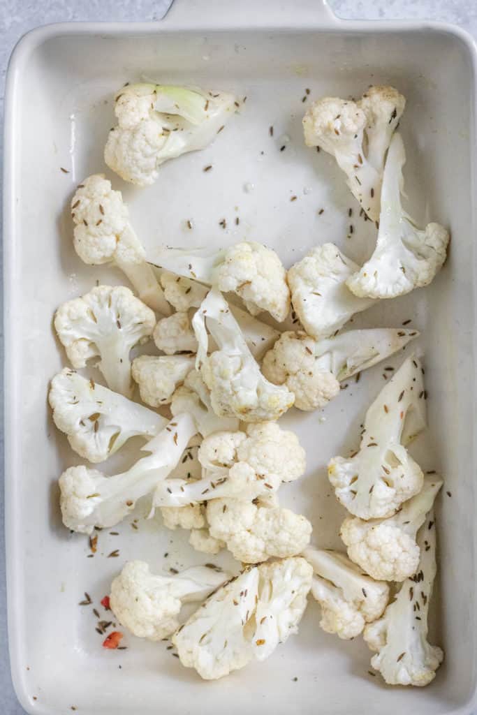 Cauliflower prepped in a baking dish ready to roast in the oven.