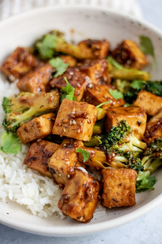 Close up side view of the tofu stir fry served with white rice in a bowl.
